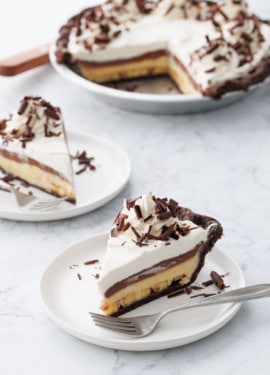 Chocolate Banana Cream Pie with Flaky Chocolate Pie Crust sliced on white plates on marble background.