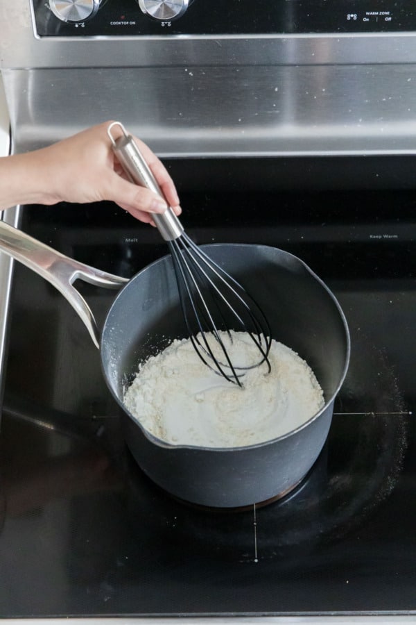 Whisking sugar with flour and cornstarch in a small saucepan.