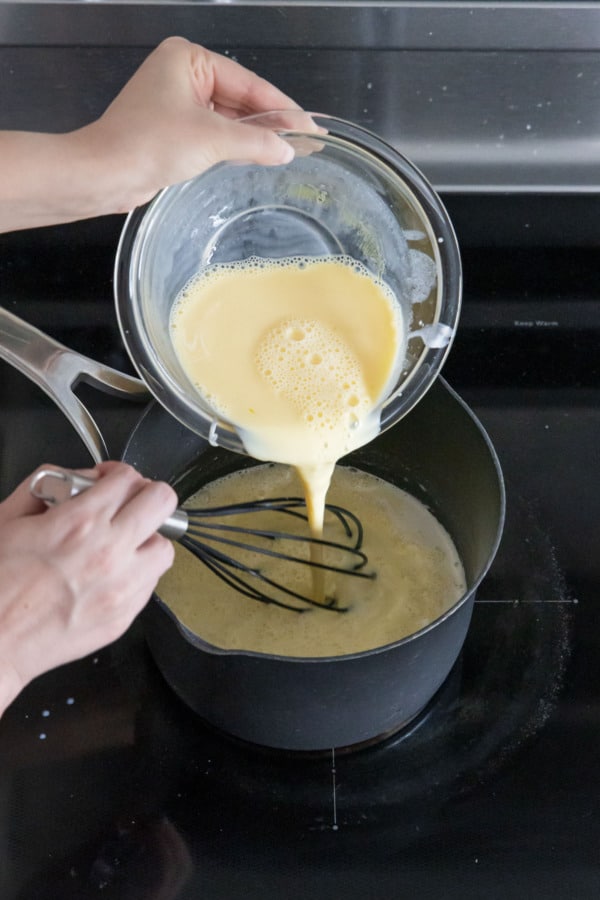 Returning tempered egg yolks to saucepan with remaining milk mixture.