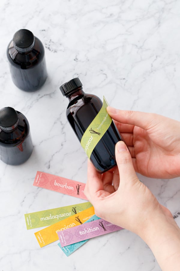 Adhering the labels, green bands wrapped diagonally around the 4oz bottles of vanilla extract.