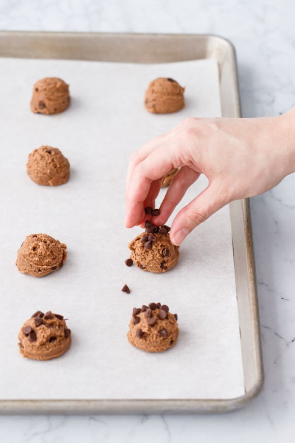 Pressing a few more mini chocolate chips onto the top of the unbaked dough balls.