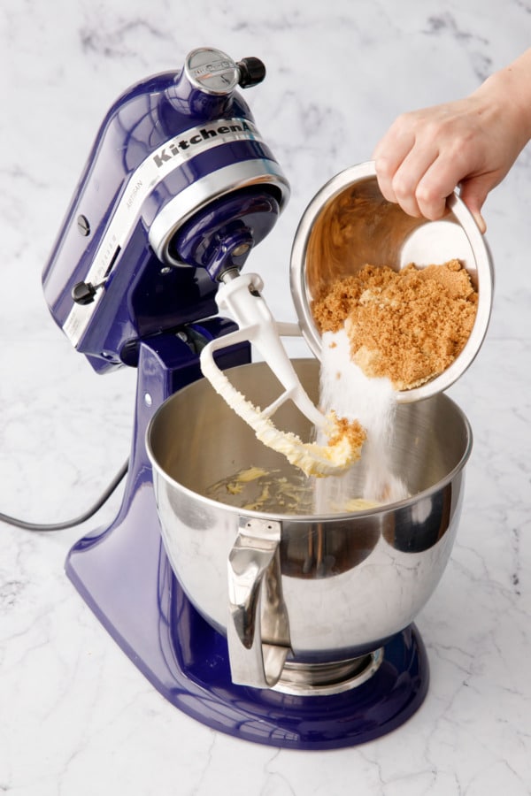 Pouring sugar and brown sugar into bowl of stand mixer along with creamed butter.