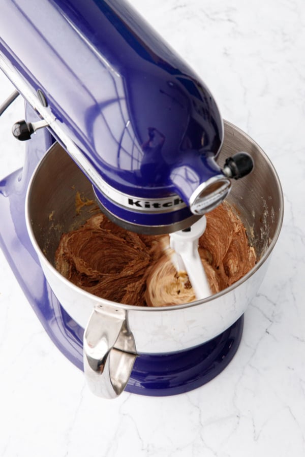 Mixer stirring brown Nutella into light golden batter until the color is even.