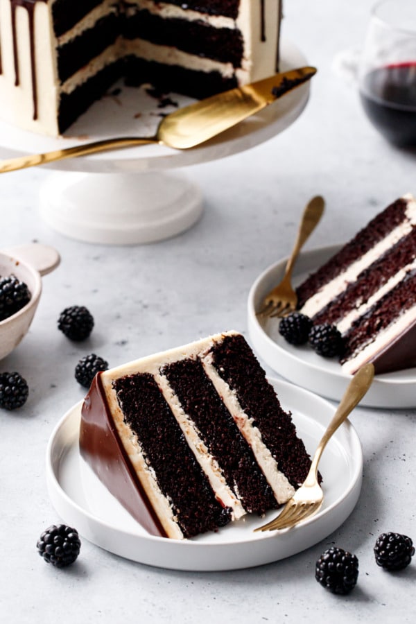 Closeup, slice of Blackberry Red Wine Chocolate Cake showing the distinct layers of dark cake, ivory buttercream, and blackberry jam in between.