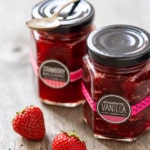 Jars of Strawberry Vanilla and Strawberry Balsamic Jam on a rustic wood background.