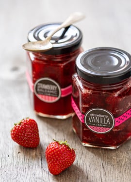 Jars of Strawberry Vanilla and Strawberry Balsamic Jam on a rustic wood background.