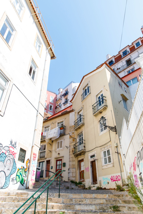 Looking up a steep street at pastel colored buildings in Lisbon, Portugal