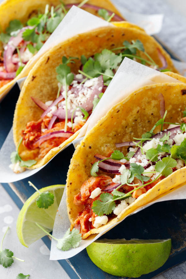 Close up of chicken tinga tacos in corn tortillas with a slice of lime.