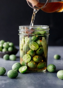 Pouring the cider vinegar-based brine into a jar packed with cucamelons.