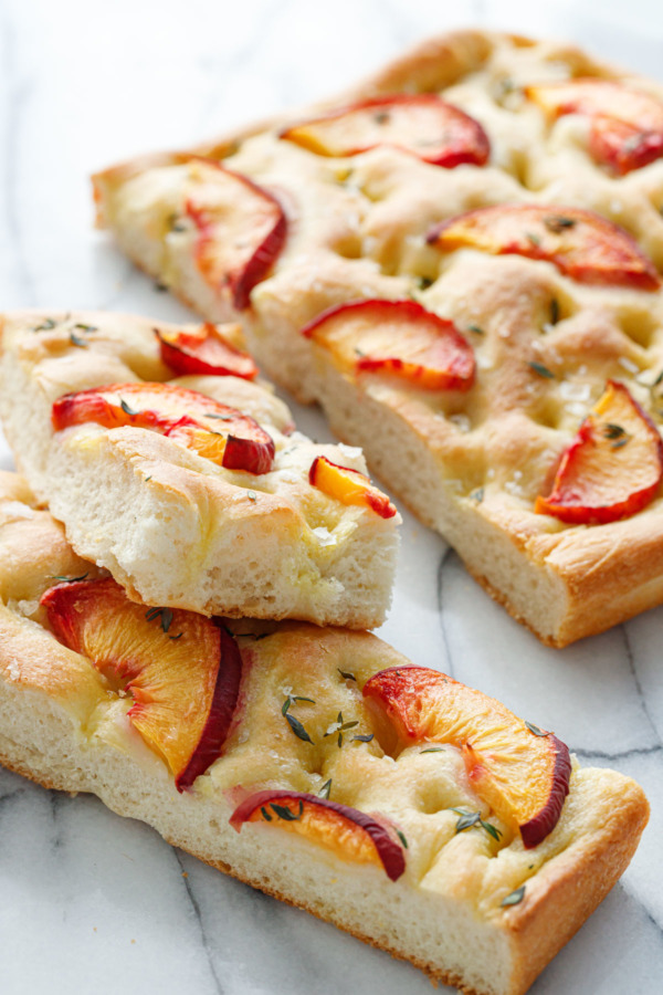 Peach & Fresh Herb Focaccia Bread cut into slices on a marble background
