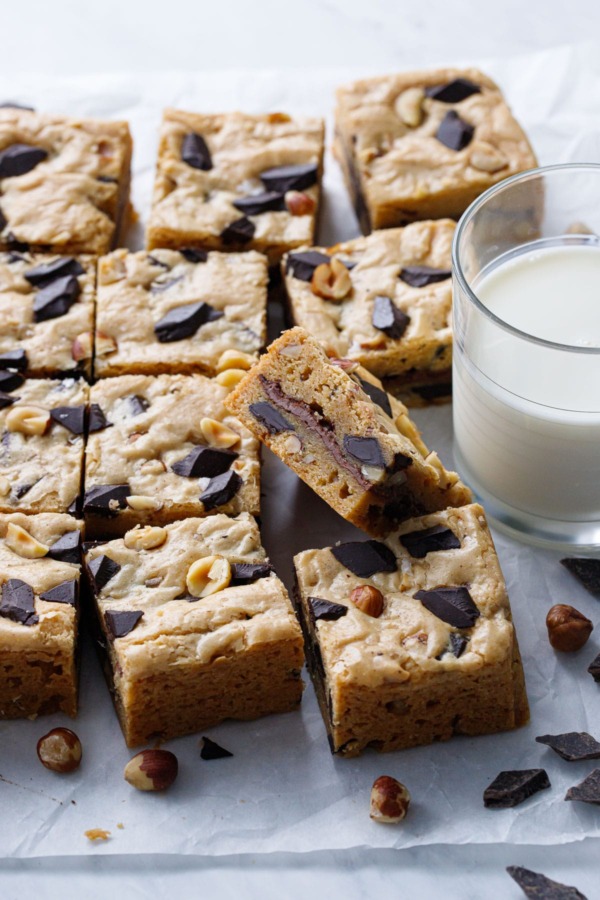 Nutella-Stuffed Brown Butter Blondies cut into squares with a glass of milk on the side.