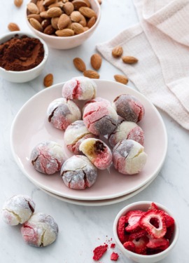 Plate with Neapolitan Amaretti Cookies, and bowls of strawberries, cocoa poweder and almonds.