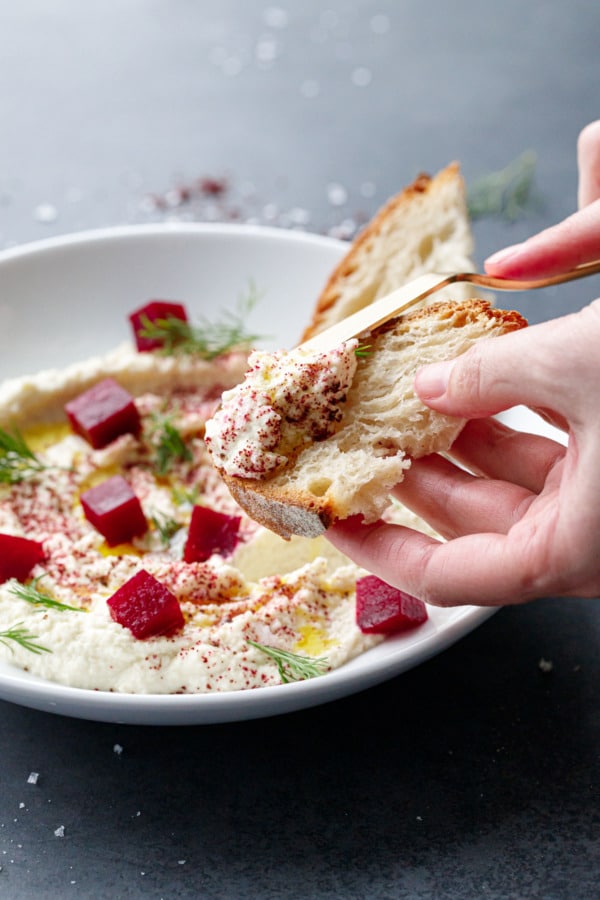 Spreading whipped almond dip on a slice of fresh sourdough bread