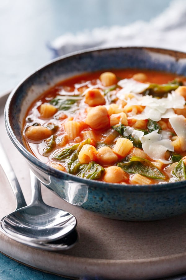 Side view of Italian Pasta and Chickpea Stew with escarole, topped with shaved pecorino cheese