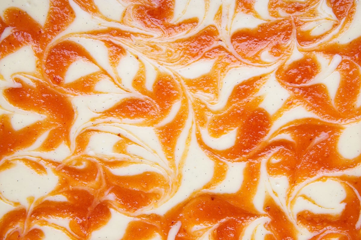 Closeup of cheesecake bar texture with a swirl of orange peach puree