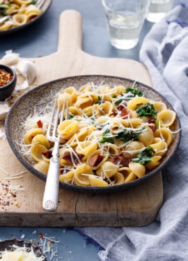 Bowl of orecchiette on a vintage wood board with a silver fork
