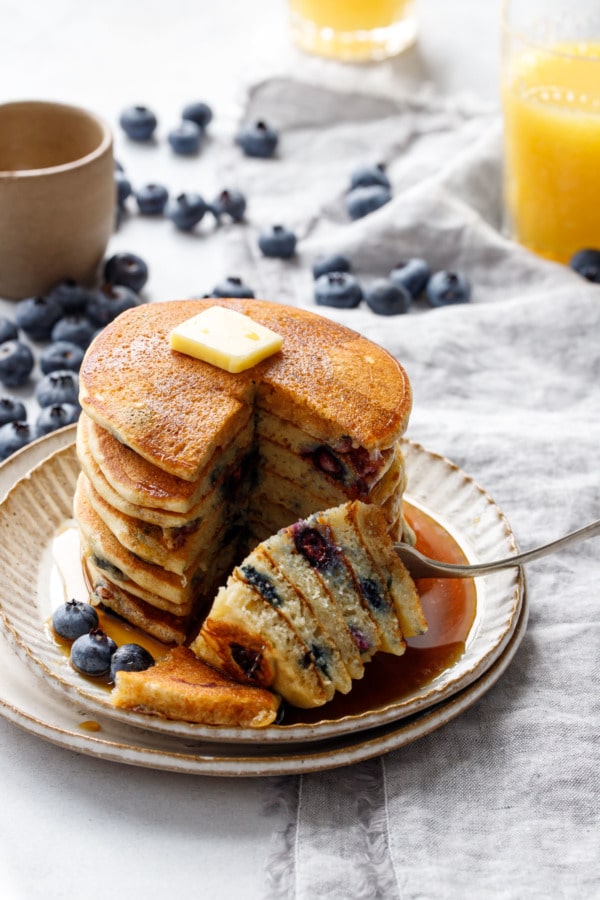 Cutting into a stack of blueberry pancakes to show the fluffy texture