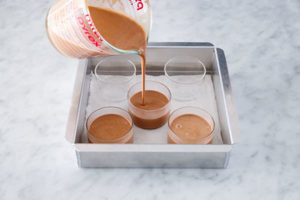 Pouring the creme custard base into glass ramekins, set inside a cake pan