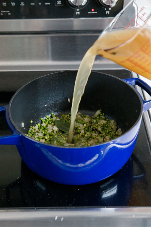 Pouring chicken broth into a large stock pot with split peas