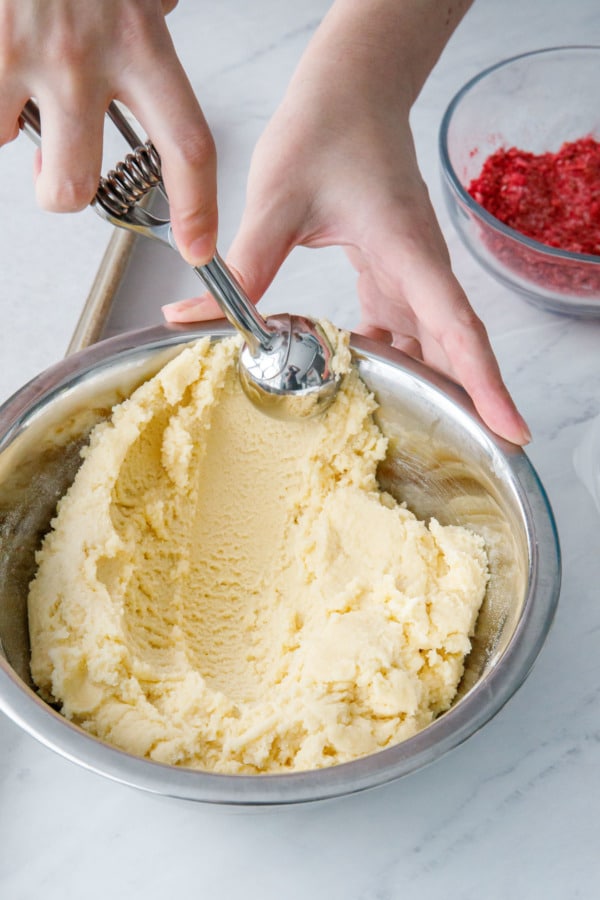 Scooping balls of sugar cookie dough with a small cookie scoop