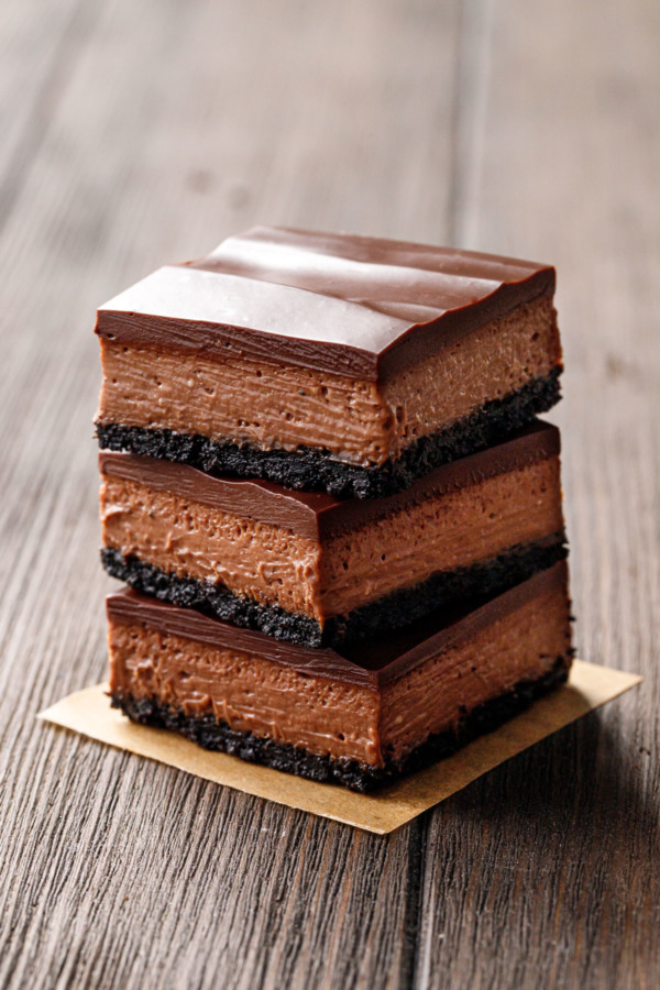 Stack of three Chocolate Chai Cheesecake Bars on a wood background