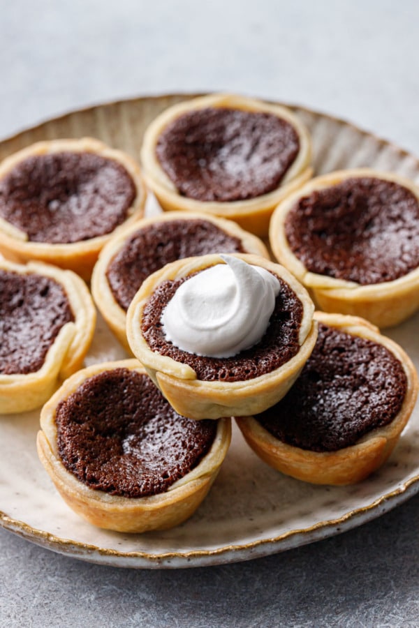 Stack of Mini Bourbon Fudge Pies on a plate, one topped with a swirl of whipped cream