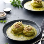 Dark gray bowls with Hungarian Stuffed Kohlrabi (one bigger and one smaller bulb) surrounded by a green kohlrabi green puree