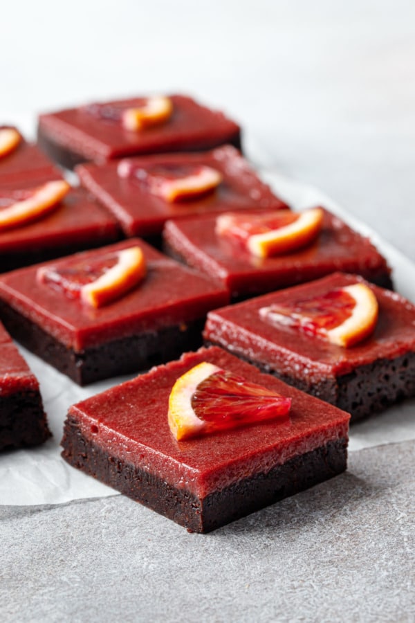 Cut squares of Blood Orange Curd Brownies showing the perfectly defined layers of dark chocolate brownie and vibrant red blood orange curd.