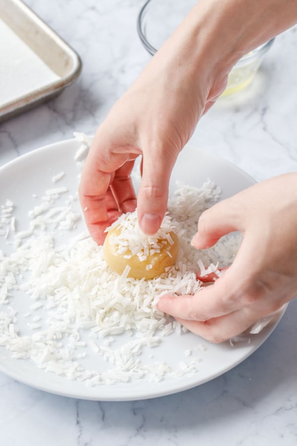 Rolling ball of dough in shredded coconut.