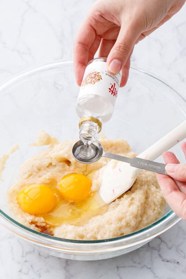 Measuring coconut extract in a silver 1 teaspoon measuring spoon.