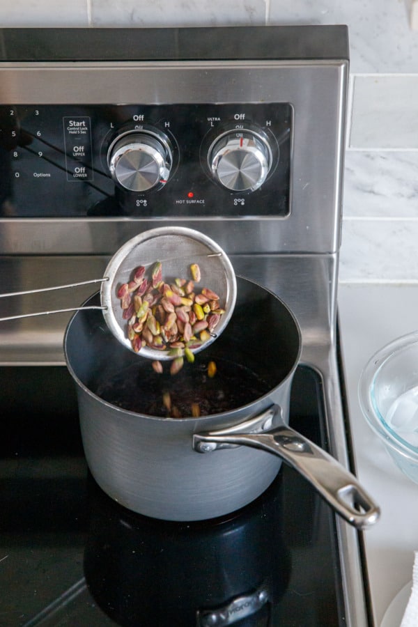 Blanching pistachios by dumping shelled nuts into a pot of boiling water.