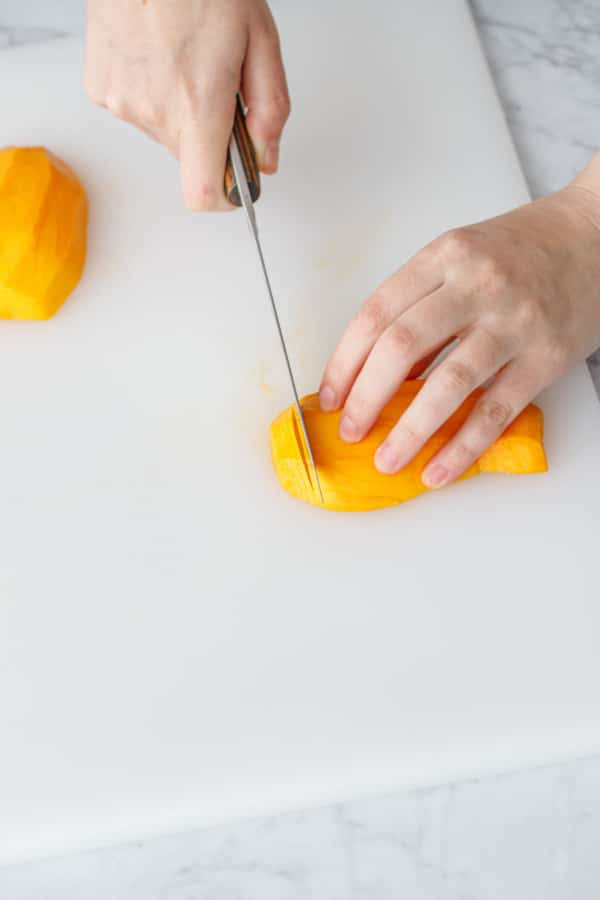 Slicing the mango into thin slices to make the mango flowers.
