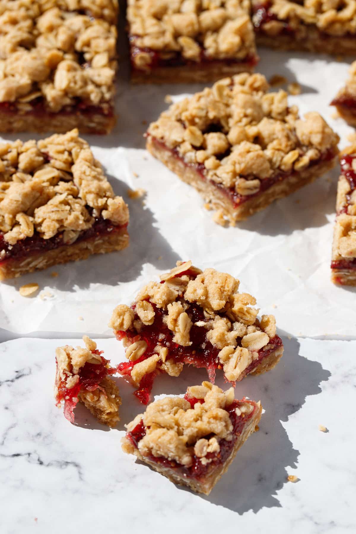 Fig, Apple & Vanilla Crumb Bar pulled apart in the foreground to show the jammy texture of the fig apple layer.
