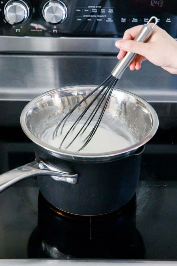 Whisking egg white and sugar mixture in a double boiler on the stovetop.