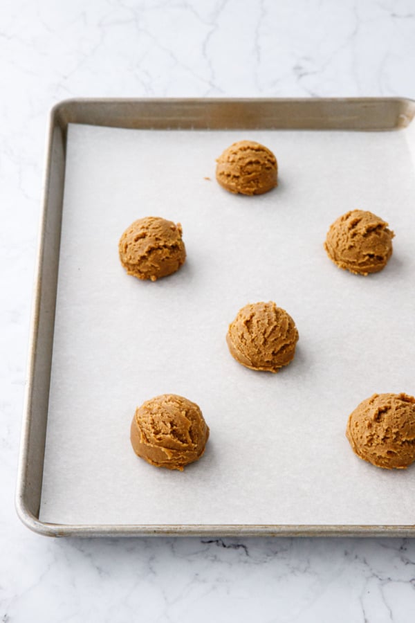 Cookie dough balls before baking on a parchment-lined baking sheet.