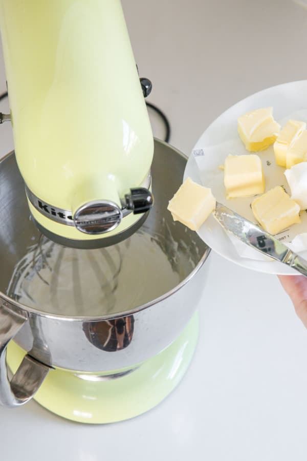 Tipping a chunk of butter into a stand mixer with the egg white meringue.