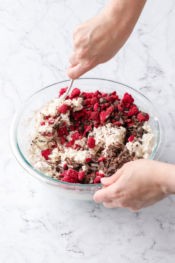 Mixing in chocolate and raspberries to dough until evenly distributed.