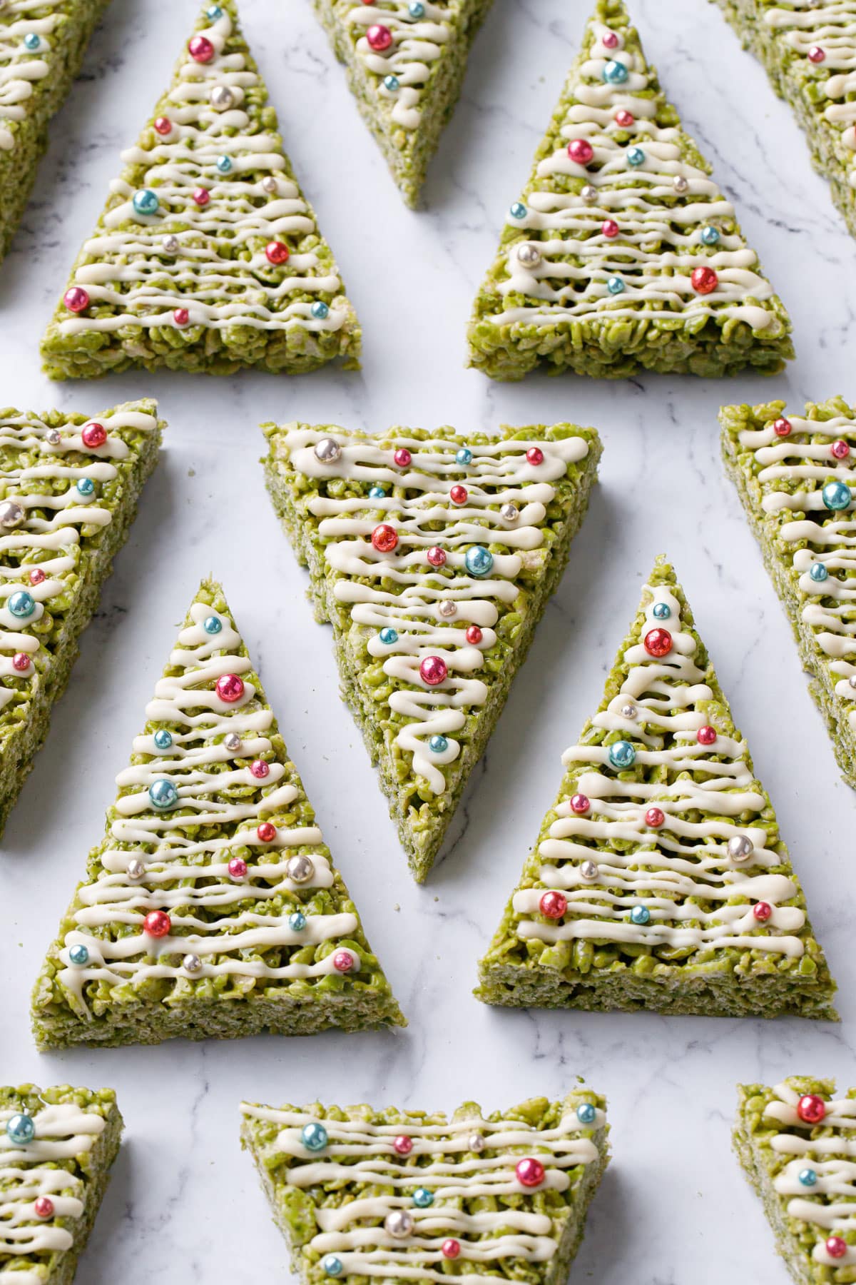 Even rows of triangular Matcha Rice Crispy Treats decorated to look like Christmas trees.