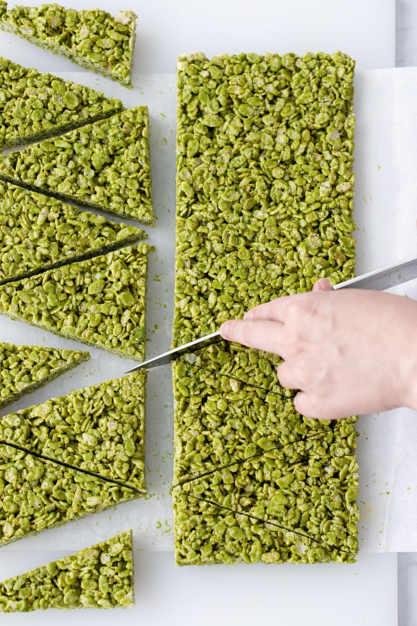 Cutting Matcha Rice Crispy Treats diagonally into tree-shaped triangles.