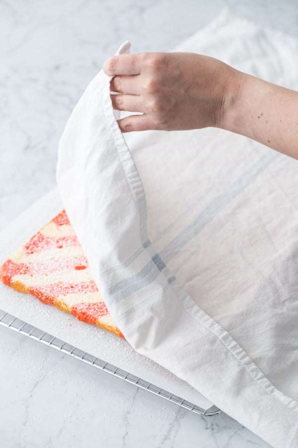 Covering cake roll with a white tea towel.