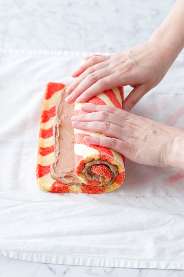 Continuing to roll up the cake roll, you can begin to see the signature spiral of cake and filling forming on the side.