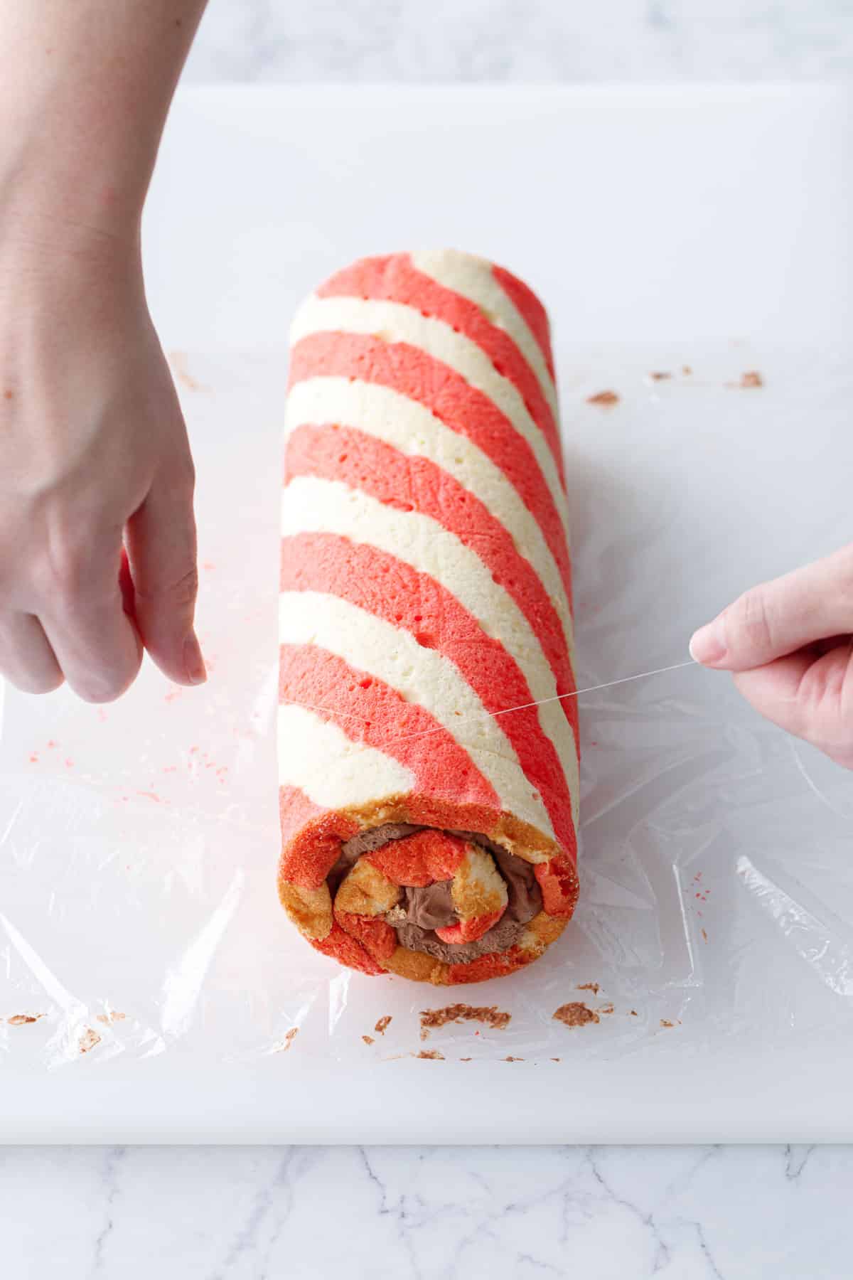 Slicing a finished cake roll using a piece of fishing line, wrapped around the cake and then pulled across.