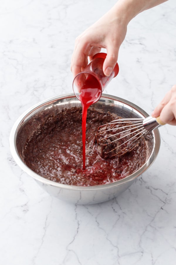 Whisking blood orange juice into partially mixed chocolate cupcake batter.