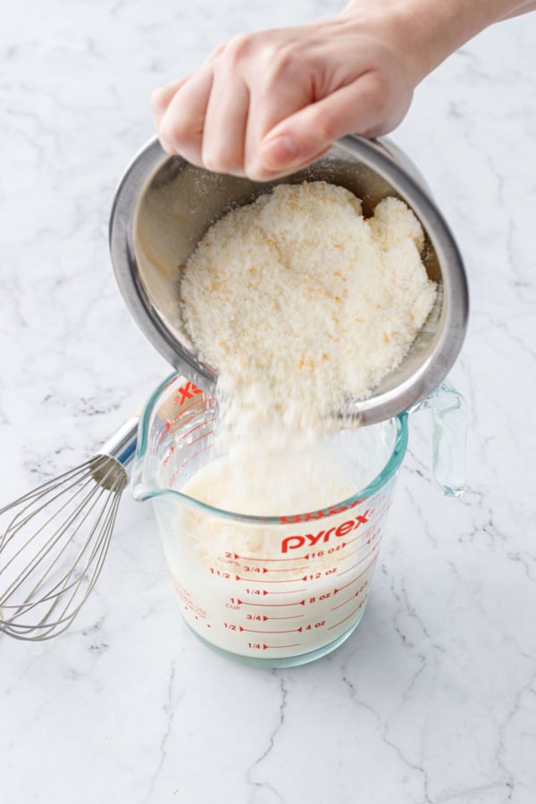 Pouring orange sugar mixture into measuring cup along with egg and milk.