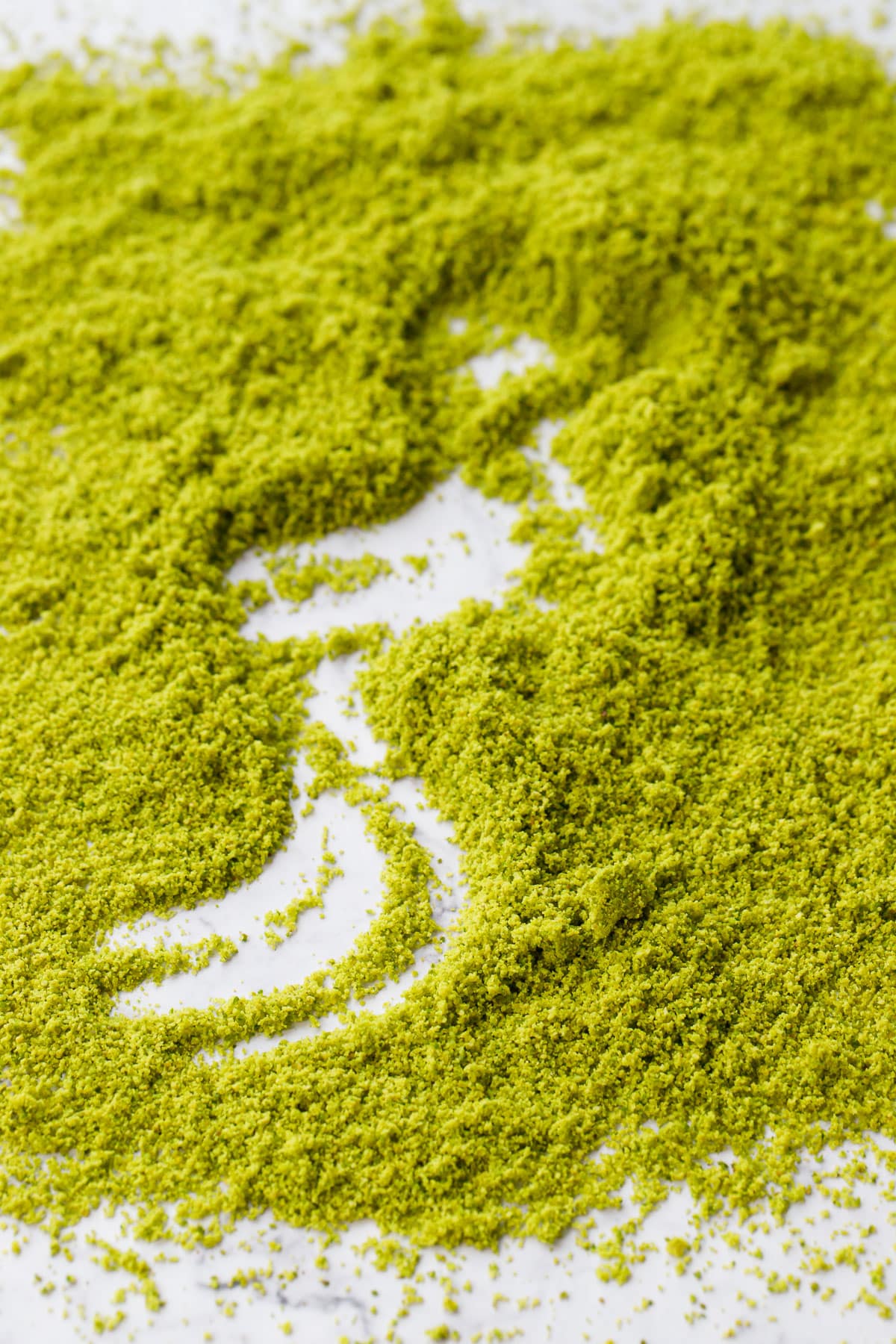 Layer of homemade pistachio flour with a squiggle dragged through the middle showing the marble background underneath.