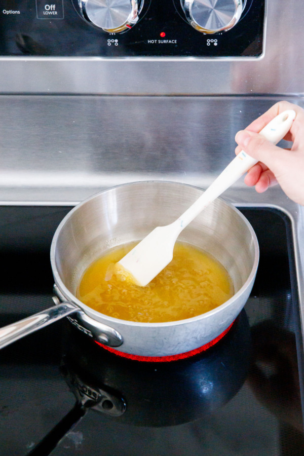 Simmering passionfruit juice, sugar and corn syrup in a small saucepan on the stovetop.