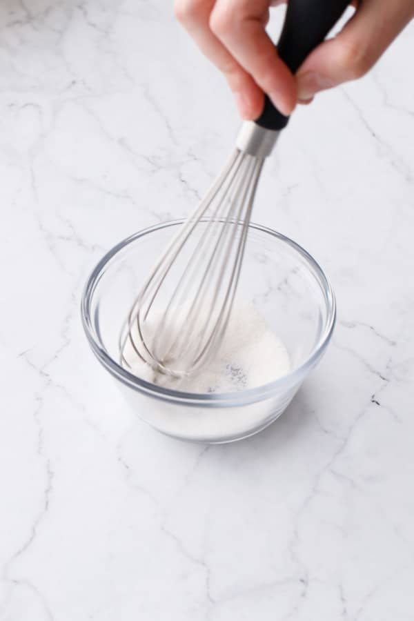 Whisking guar gum with granulated sugar in a small glass custard dish.