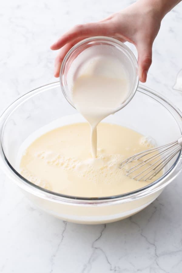 Pouring guar gum mixture into bowl with ice cream base.