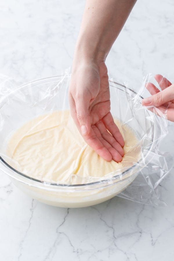 Pressing a layer of plastic wrap down onto the surface of the ice cream base before refrigerating.