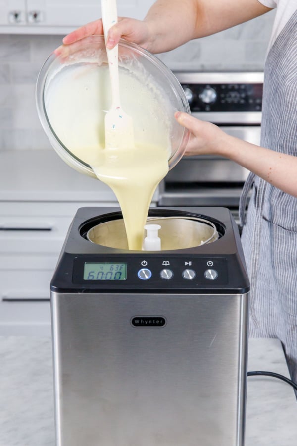 Pouring chilled ice cream base into a countertop ice cream maker.